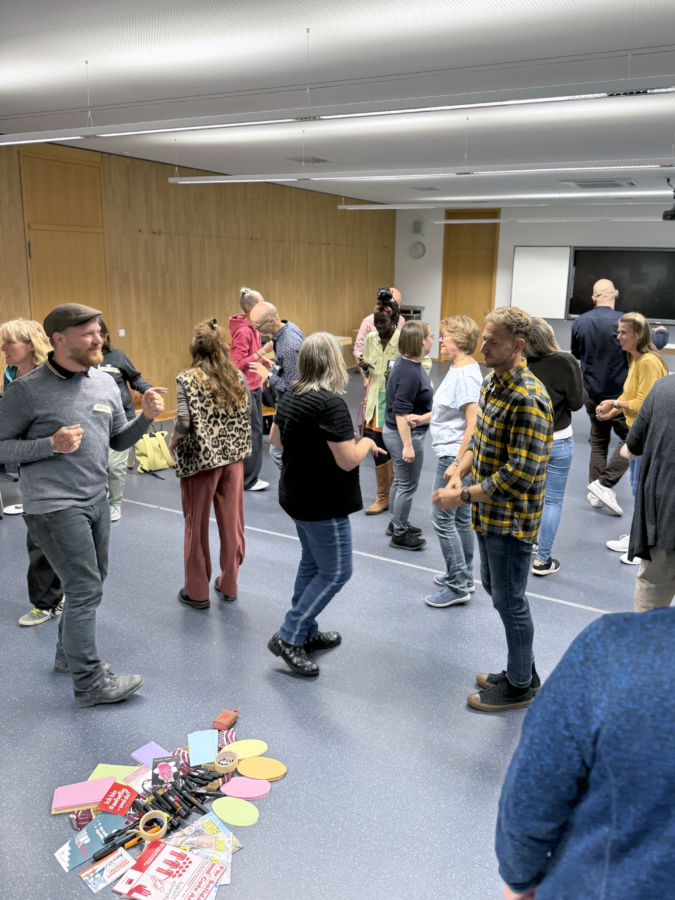 Dozent:innen tanzen und unterhalten sich am pädagogischen Studientag im Auditorium der Fachakademie